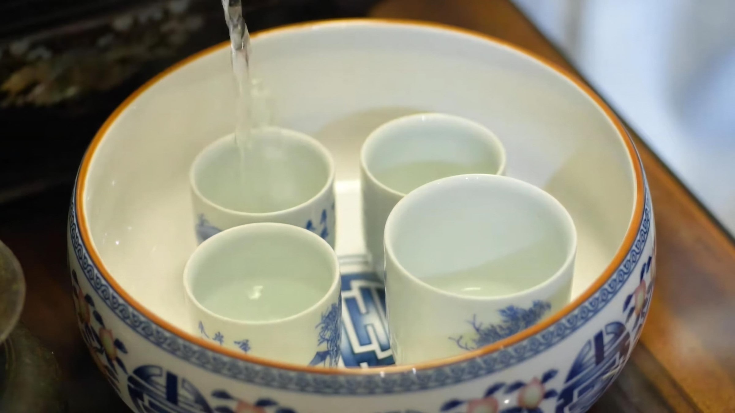 place-serving-cups-in-tea-basin-and-pour-boiling-water